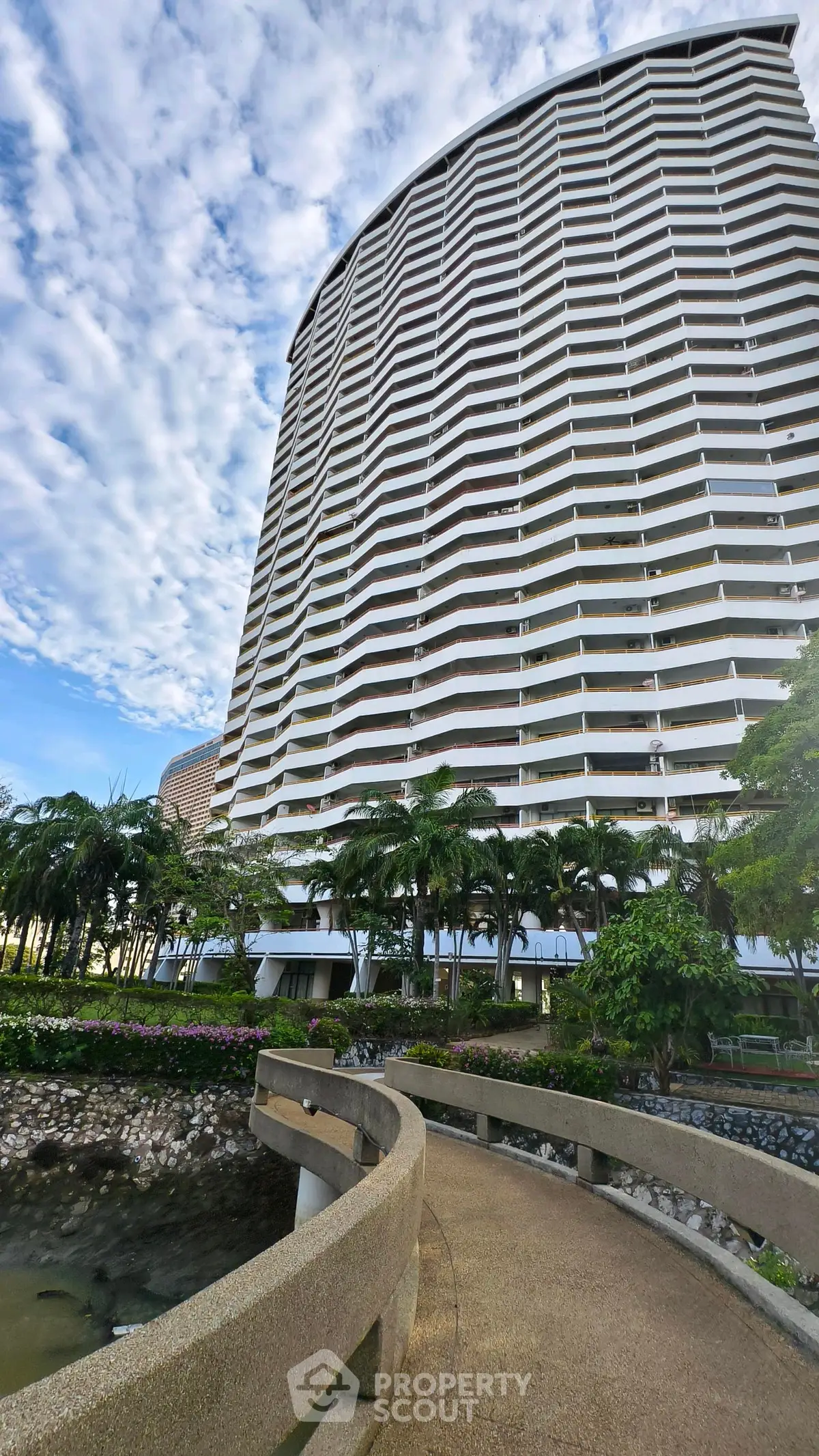 Stunning high-rise building with lush landscaping and a serene walkway, perfect for urban living.