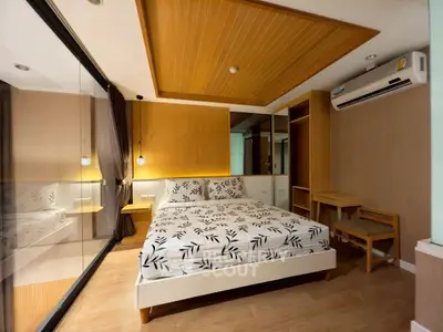 Modern bedroom with stylish wooden ceiling and glass partition, featuring a cozy bed and air conditioning.