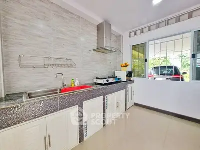Modern kitchen with sleek countertops and gas stove, featuring ample natural light.