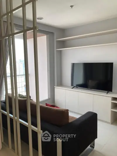 Modern living room with sleek TV setup and city view from window.