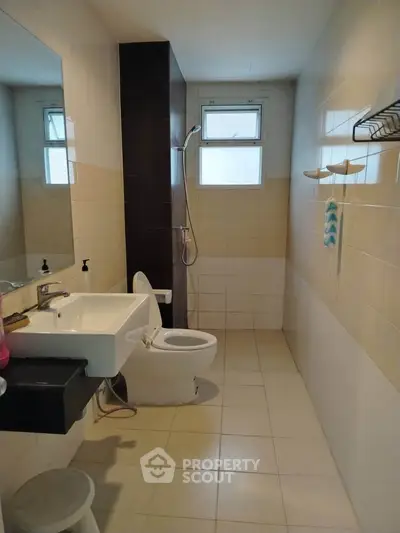 Modern bathroom with shower, sink, and toilet in a sleek tiled design.