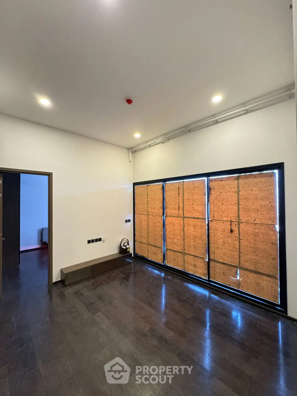 Spacious empty room with large windows and dark wooden flooring