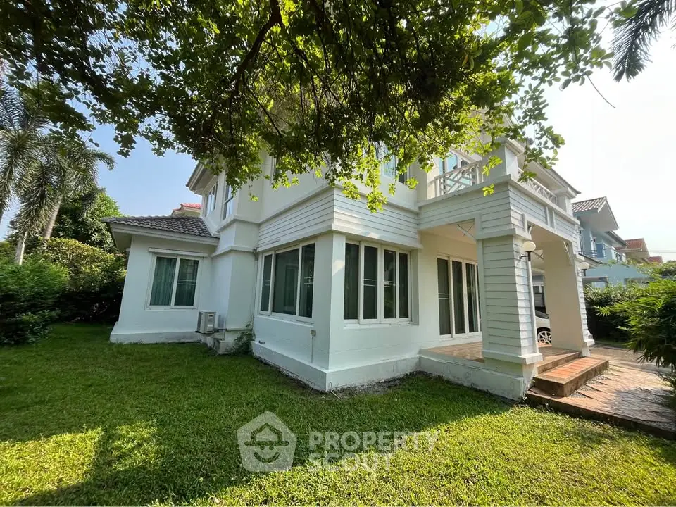 Charming two-story white house with lush green garden and spacious lawn