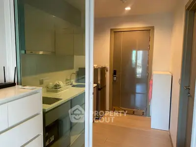 Modern apartment entrance with sleek kitchen and ample storage space.