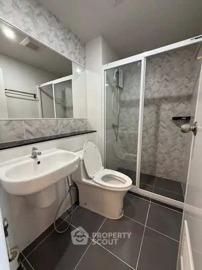 Modern bathroom with sleek fixtures and spacious shower in contemporary apartment.