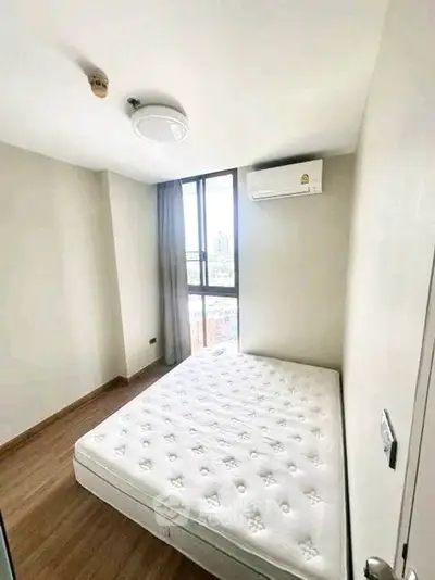 Cozy bedroom with large window and air conditioning in modern apartment.