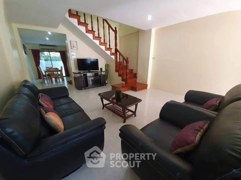 Spacious living room with elegant staircase and cozy seating area.