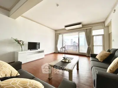Spacious living room with modern decor and city view, featuring elegant furniture and large windows.