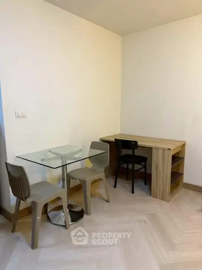 Minimalist study area with glass table and wooden desk in modern apartment.