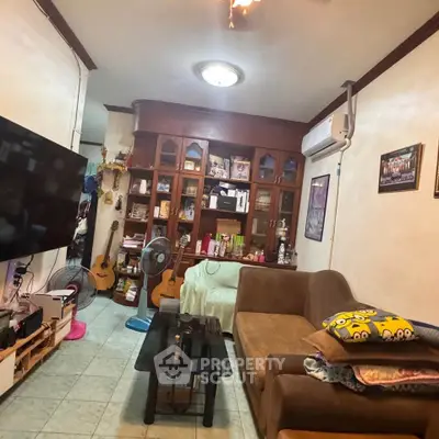Cozy living room with brown sofa, wall-mounted TV, and decorative wooden cabinet.