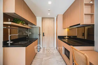 Modern kitchen with sleek wooden cabinetry and black countertops, featuring a built-in oven and stylish lighting.