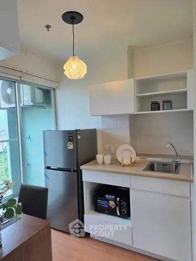 Modern kitchen with sleek appliances and stylish lighting in a cozy apartment setting.