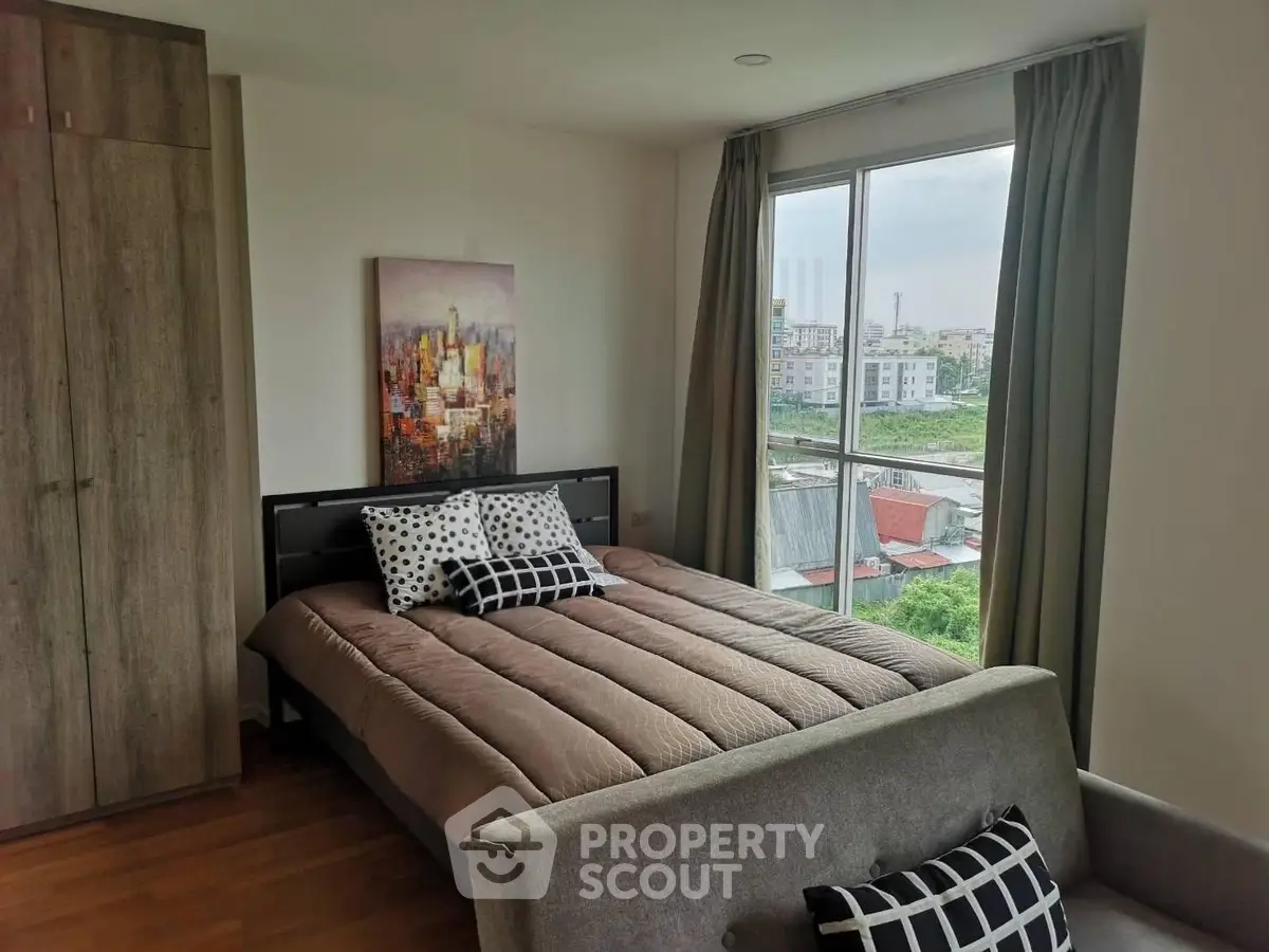 Cozy bedroom with large window offering stunning city view, modern decor, and comfortable bedding.