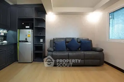 Modern living room with sleek gray sofa and compact kitchen area