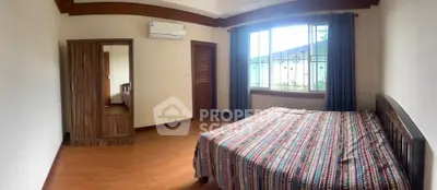 Spacious bedroom with wooden flooring and large window for natural light