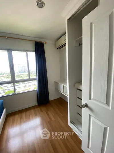 Bright bedroom with wooden flooring and large window offering city view