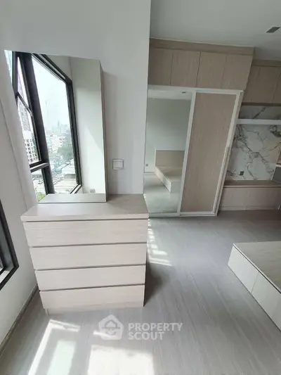 Modern bedroom with sleek built-in wardrobe and large window offering city views.