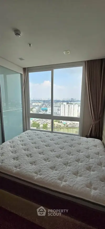 Spacious bedroom with large window offering stunning city view
