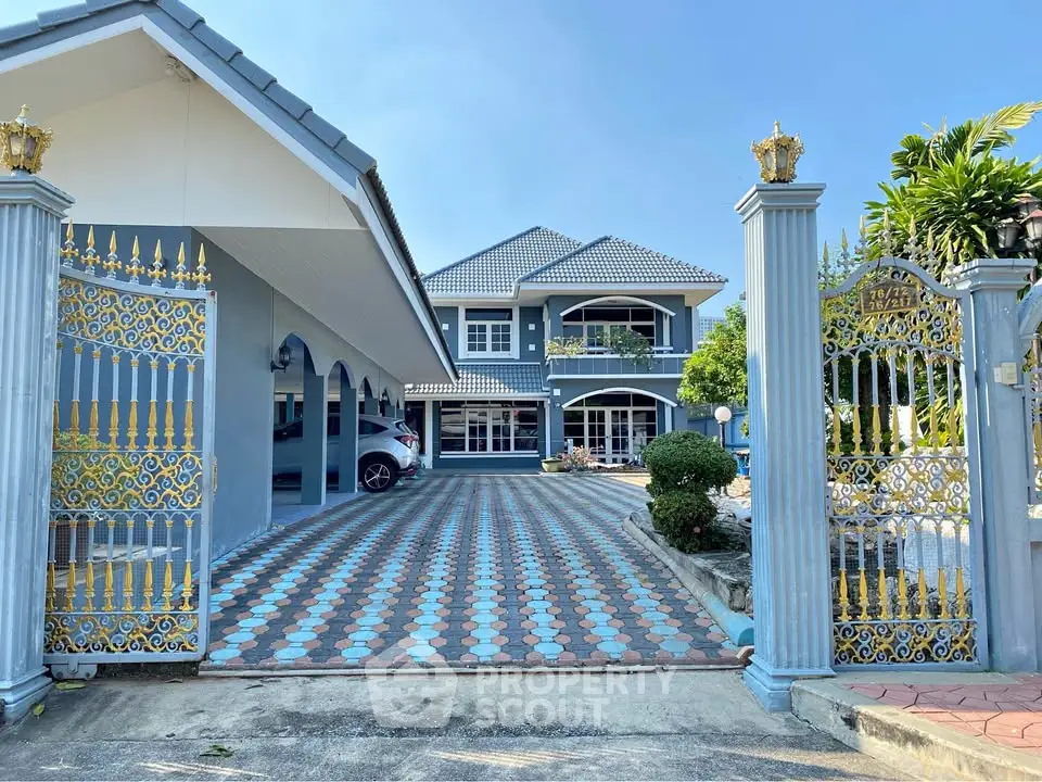 Stunning two-story blue house with elegant gated entrance and spacious driveway.