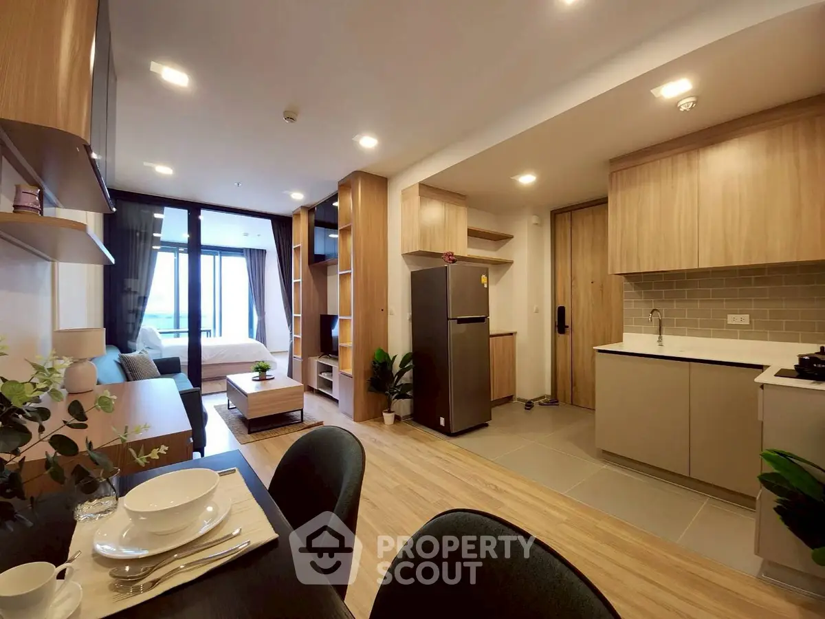 Modern open-plan apartment with stylish kitchen and cozy living area, featuring wooden accents and natural light.