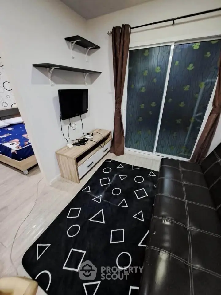 Modern living room with stylish decor and sliding glass door, featuring a cozy black sofa and geometric rug.
