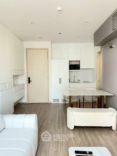 Modern living room with sleek white furniture and open kitchen layout