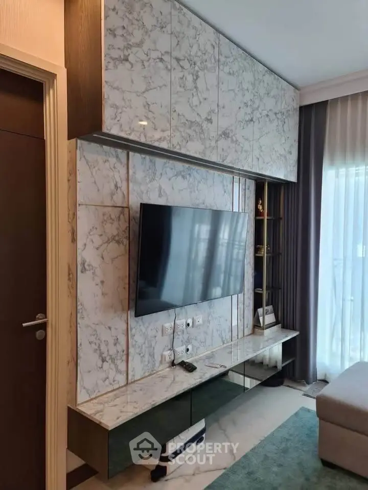 Modern living room with marble wall paneling and mounted TV, featuring sleek design and natural light.