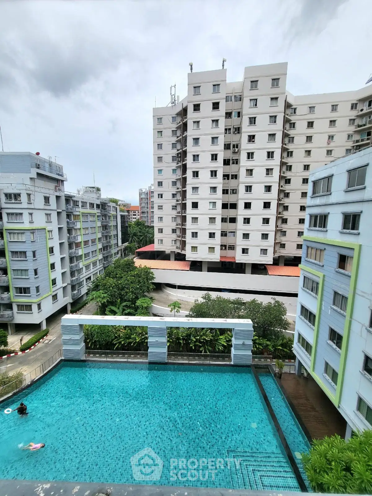 Stunning residential complex with a sparkling pool and lush greenery, offering a serene urban living experience.