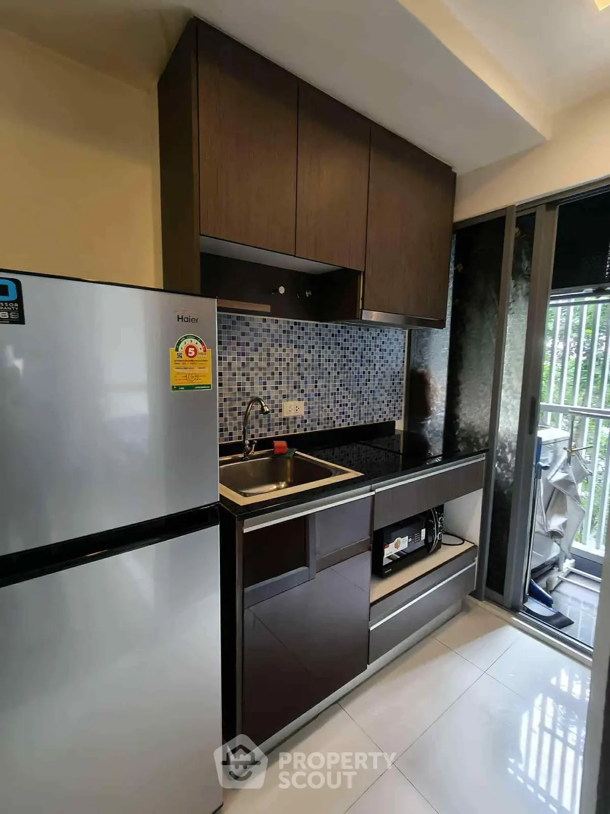 Modern kitchen with sleek cabinets and balcony view, featuring a stainless steel fridge and stylish backsplash.