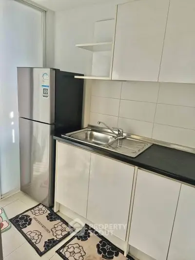 Modern kitchen with sleek cabinets and stainless steel fridge in bright apartment.