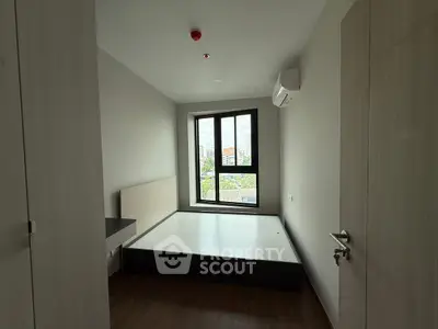 Cozy bedroom with large window and city view, featuring modern minimalist design and air conditioning.
