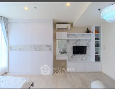 Modern living room with built-in storage and TV unit, featuring elegant marble accents and bright lighting.
