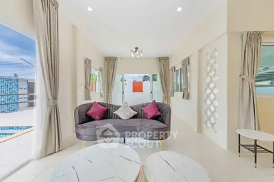 Elegant living room with modern decor and pool view, featuring stylish furniture and natural light.