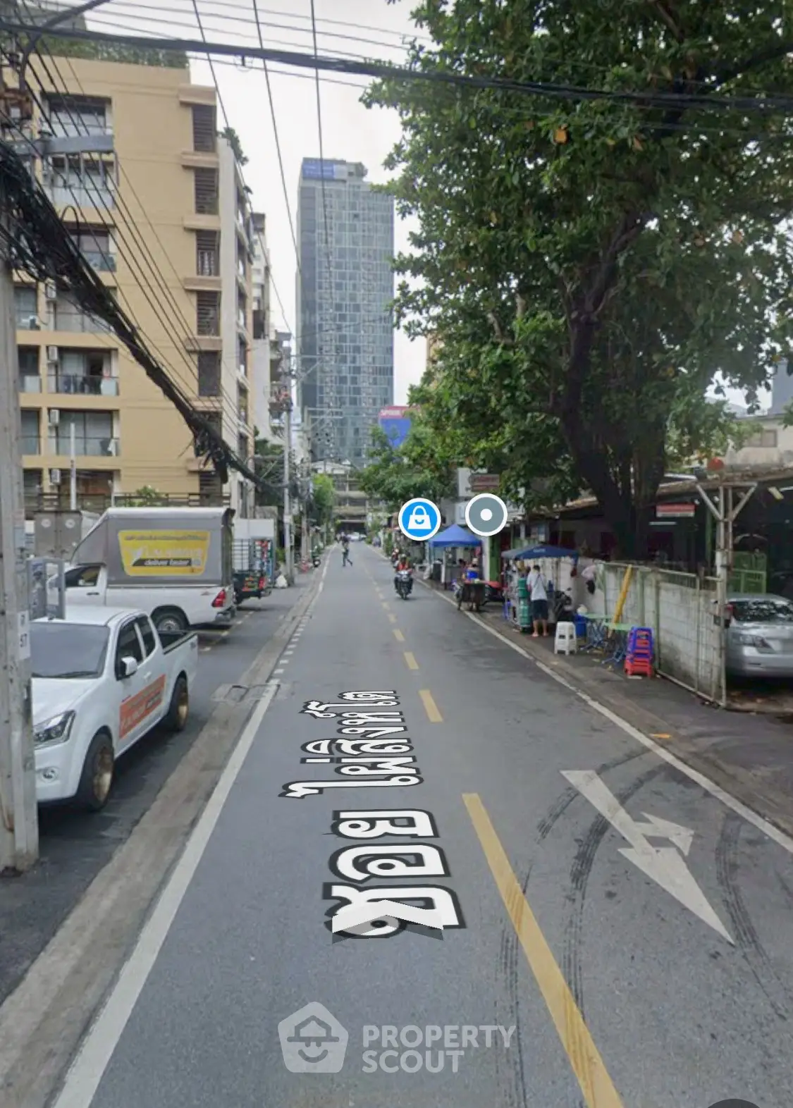 Urban street view with high-rise buildings and parked vehicles, showcasing city living.