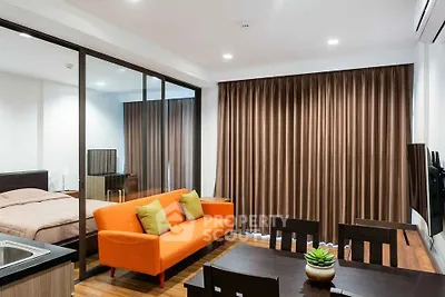 Modern studio apartment with vibrant orange sofa and sleek glass partition