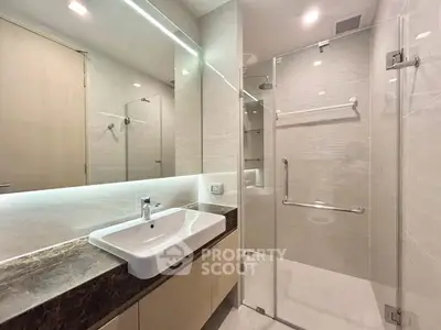 Modern bathroom with glass shower and sleek vanity in luxury apartment