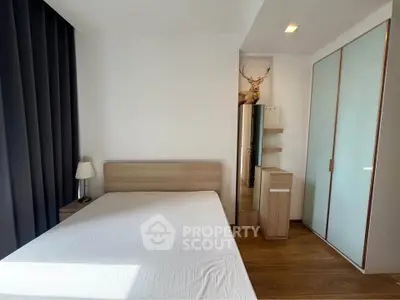 Modern bedroom with minimalist design, featuring a large bed, wooden furniture, and ample natural light.