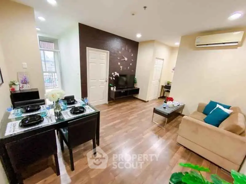 Spacious living room with modern decor and dining area, featuring hardwood floors and air conditioning.
