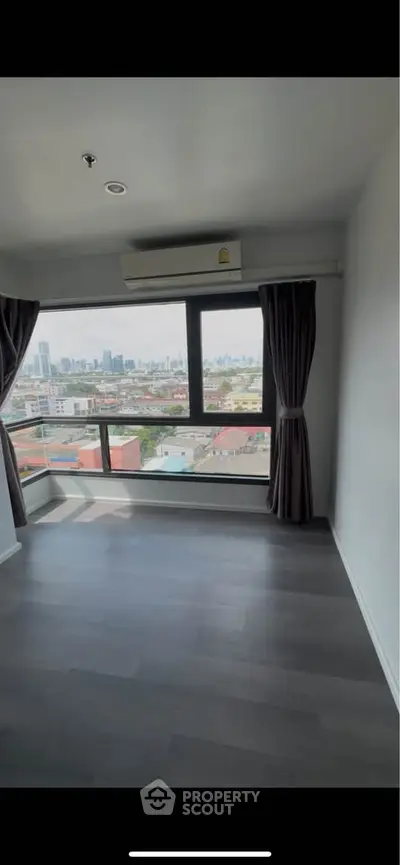 Spacious room with large window offering stunning city views, perfect for urban living.