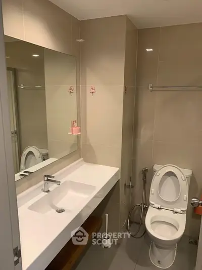 Modern bathroom with sleek fixtures and neutral tones, featuring a large mirror and contemporary design.
