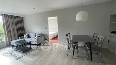 Spacious and modern living area with sleek furniture, large windows for ample natural light, and a seamless transition to a cozy bedroom.