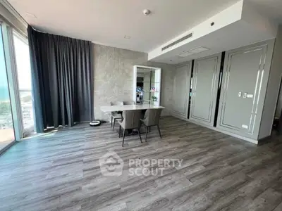 Spacious modern living room with elegant dining area and large windows offering natural light.