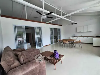 Spacious open-plan living room with modern furniture and high ceilings, perfect for entertaining.