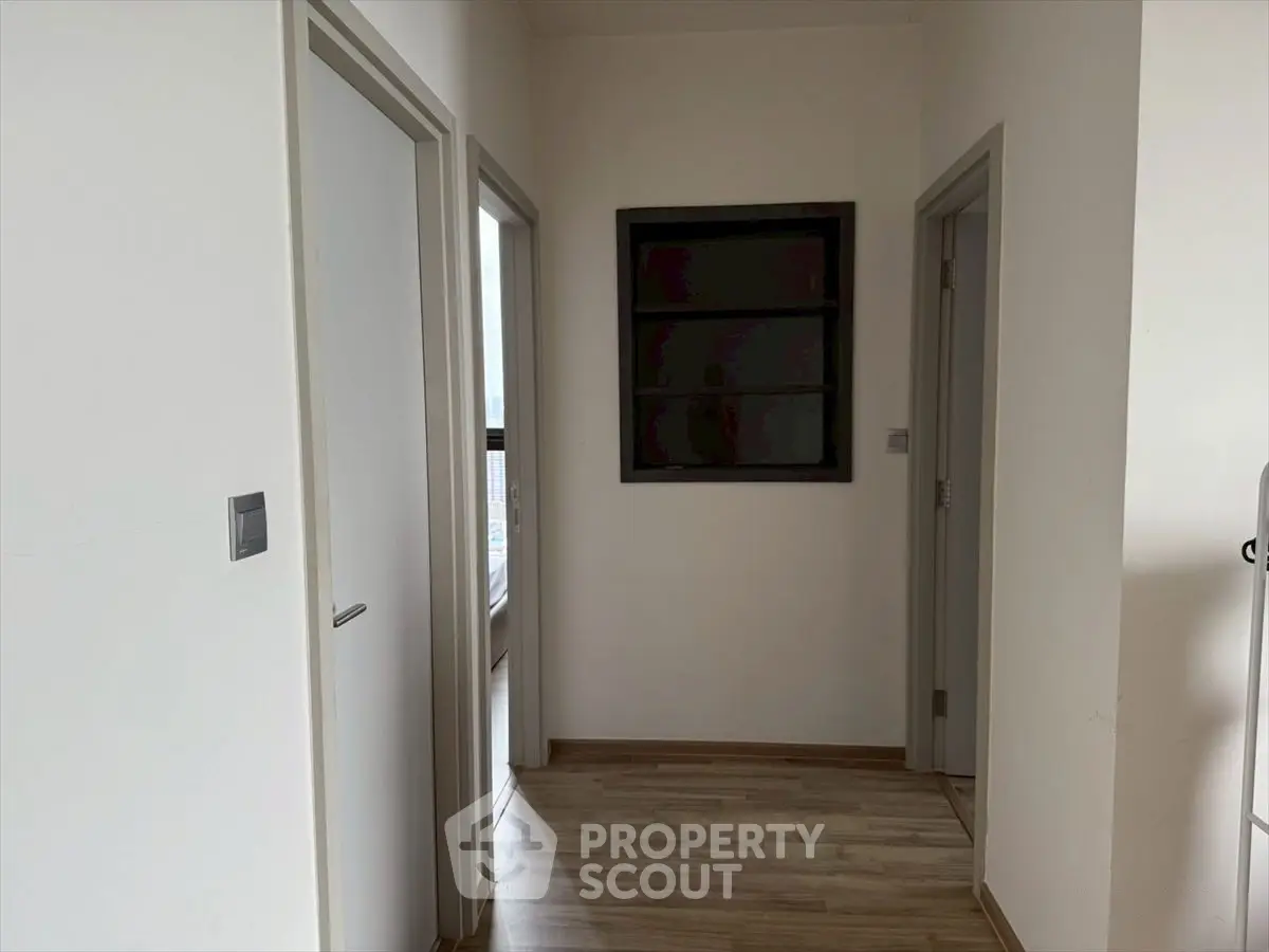 Minimalist hallway with wooden flooring and white doors in modern apartment