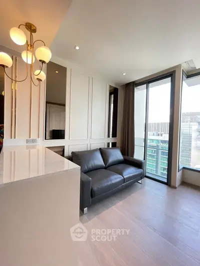 Modern living room with sleek black sofa and elegant lighting, featuring large windows with city view.