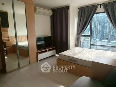 Modern bedroom with city view, featuring mirrored wardrobe and natural light.