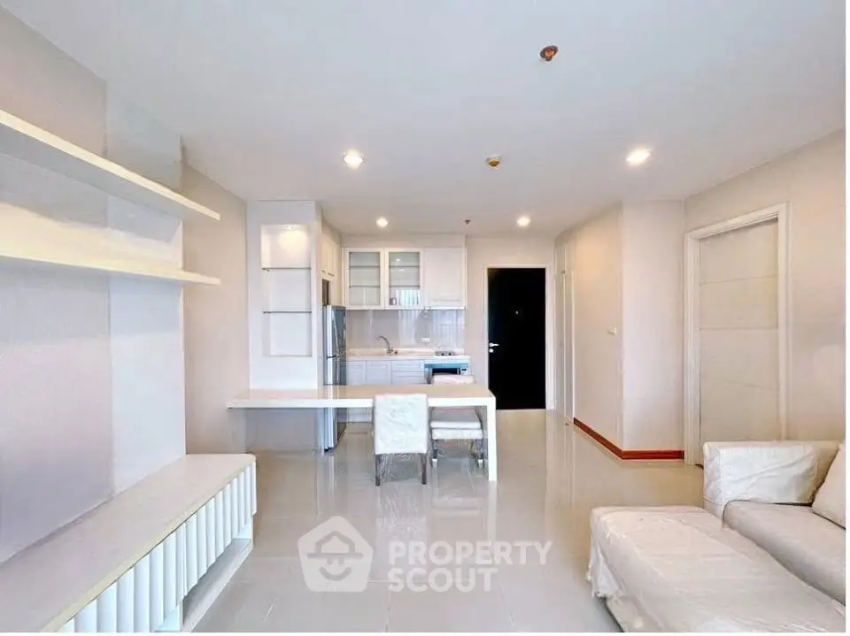 Modern open-plan living room with sleek kitchen and dining area in a bright apartment.