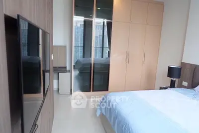 Modern bedroom with sleek wardrobe and city view, featuring a large TV and stylish decor.