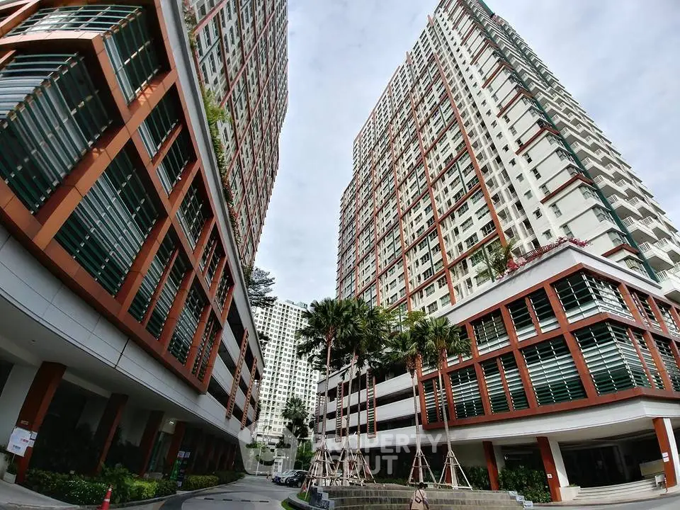 Modern high-rise residential buildings with lush landscaping and palm trees.