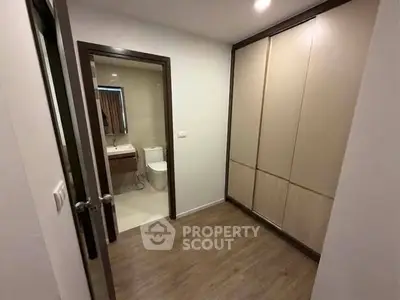 Modern apartment with spacious closet and ensuite bathroom, featuring sleek design and wooden flooring.